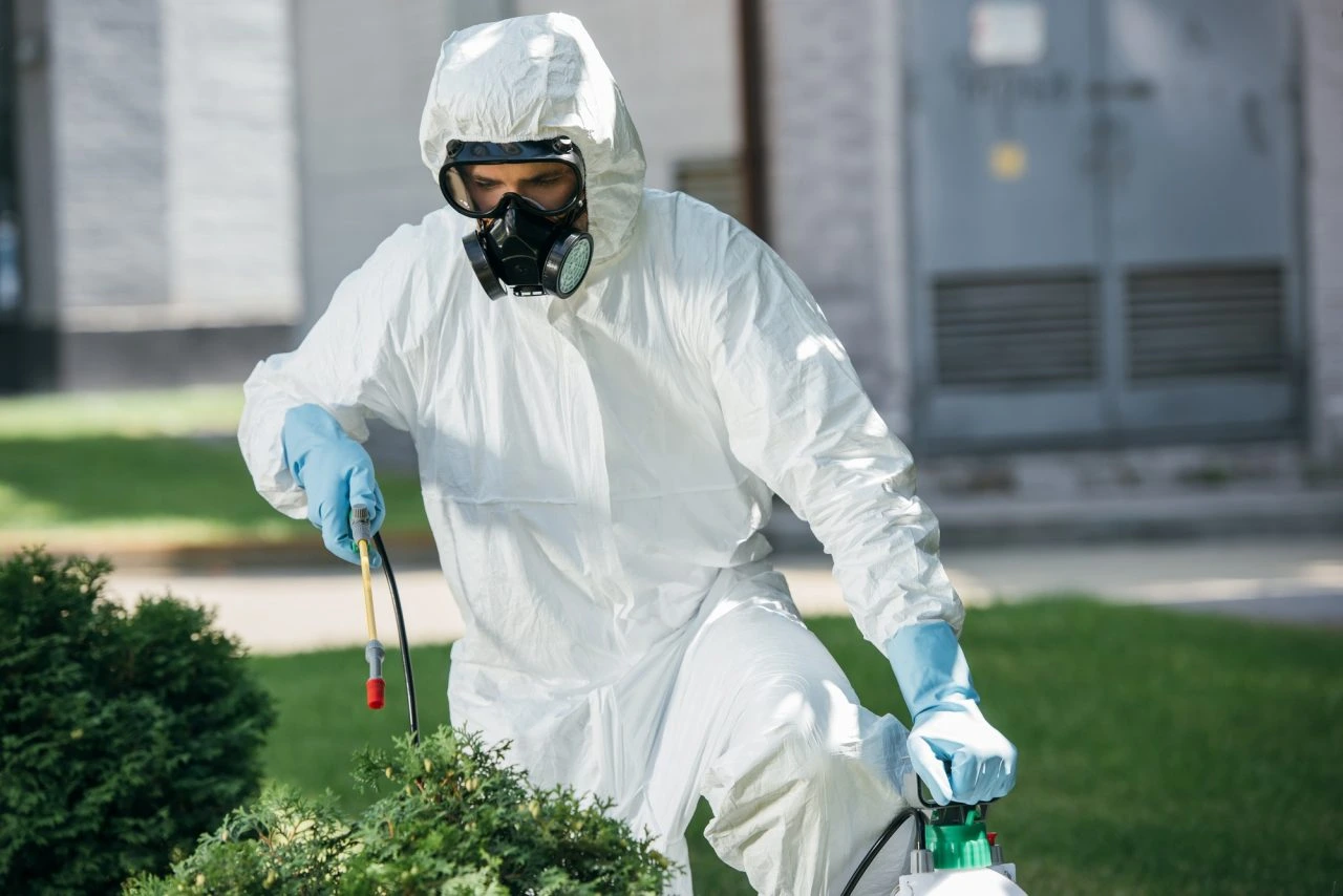 Technicien en désinsectisation appliquant un traitement anti-nuisibles dans un jardin
