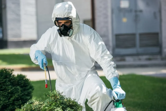 Technicien en désinsectisation appliquant un traitement anti-nuisibles dans un jardin